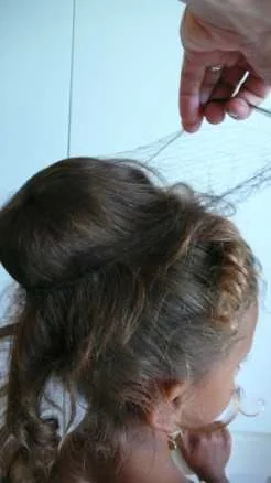 Schritt 5: … und mit dem Haarnetz fixieren: Das Netz über den Dutt ziehen, oben verdrehen …