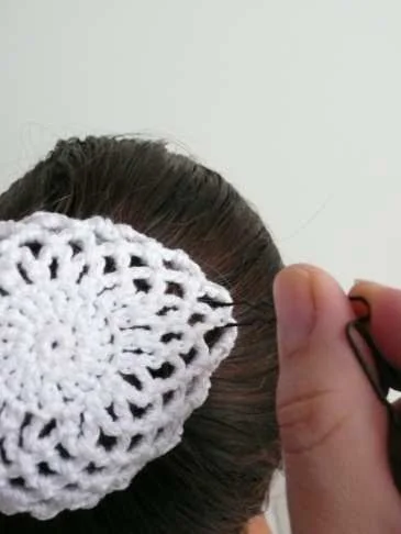 Schritt 8: Die Haarnadel etwas zur Seite ziehen und Richtung Haargummi in den Dutt schieben.